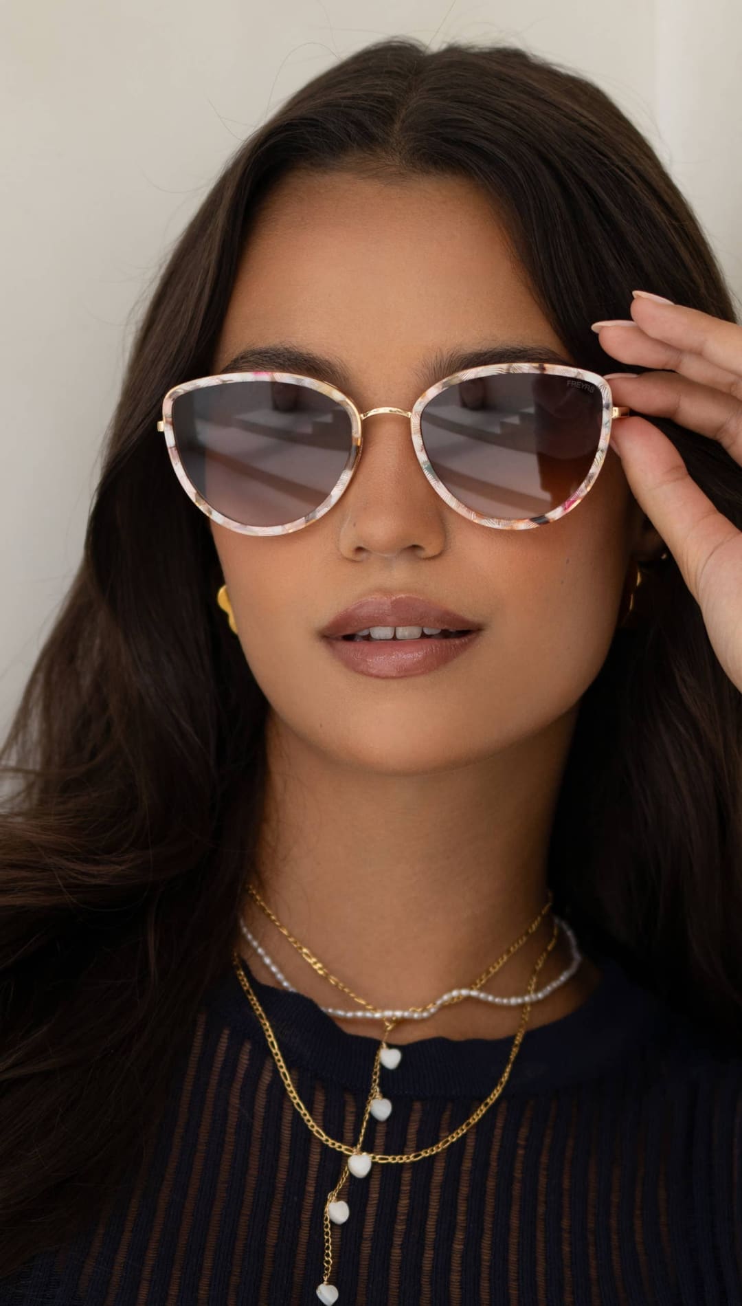 Cat-eye sunglasses with gold-toned frames and a subtle floral pattern, featuring gradient gray lenses.