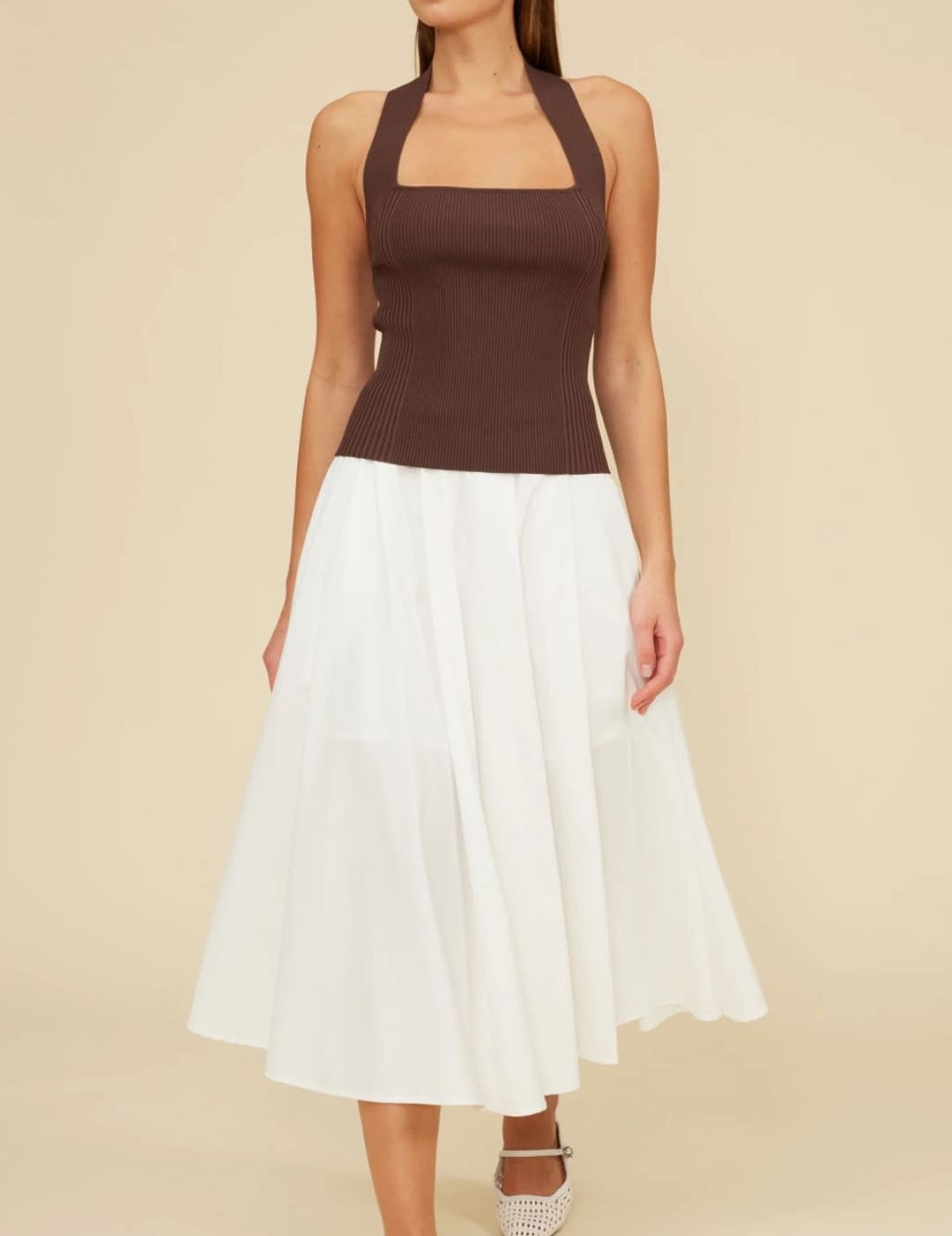 Woman in brown halter top and white skirt.