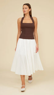 Woman in brown halter top and white skirt.