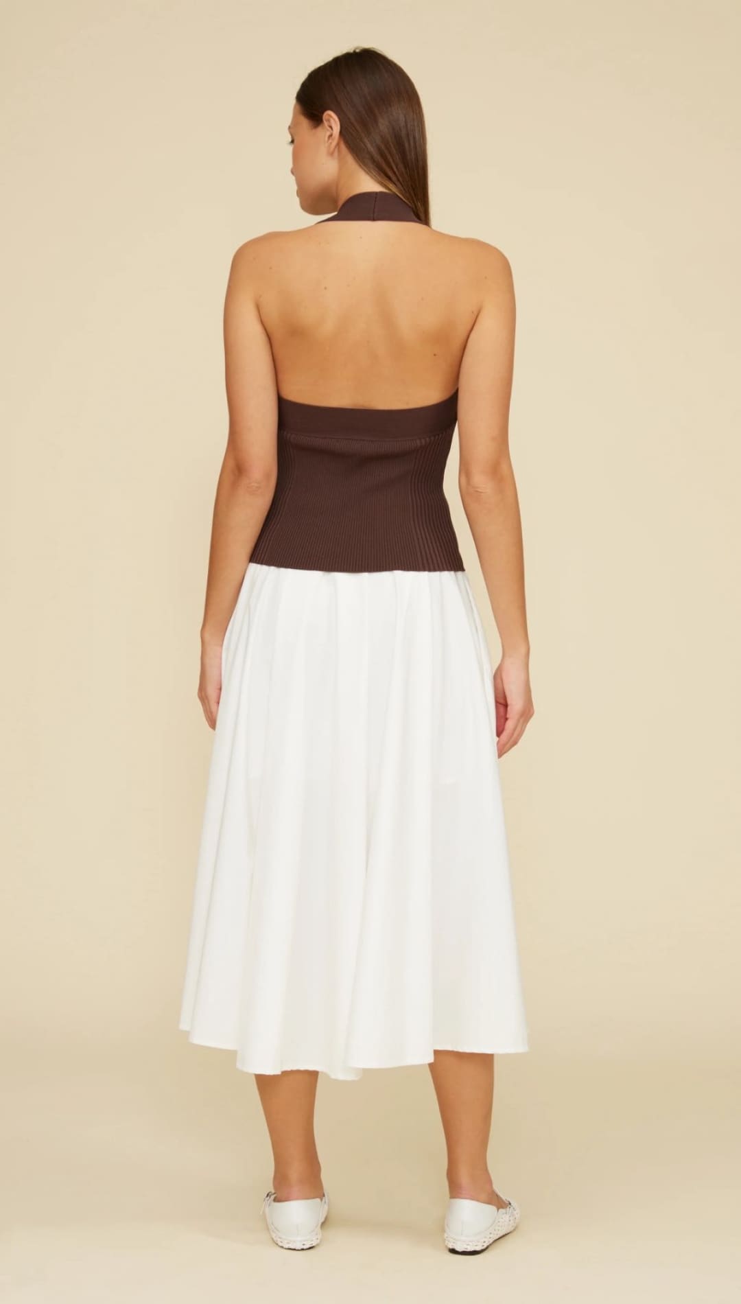 Woman in brown halter top and white skirt.