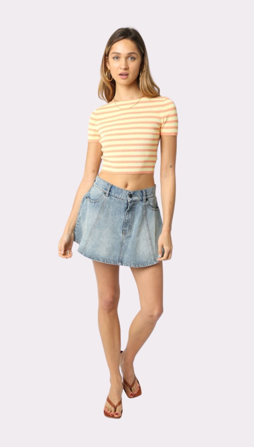 Woman in striped crop top and denim mini skirt.