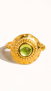 Gold-toned ring with a round, textured bezel setting a vibrant green peridot stone.