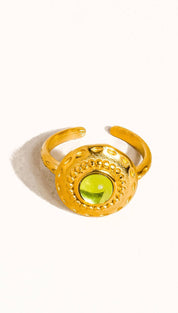 Gold-toned adjustable ring featuring a round, faceted green gemstone set in an ornate, textured bezel.