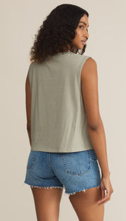 Woman in a green tank top and denim shorts.