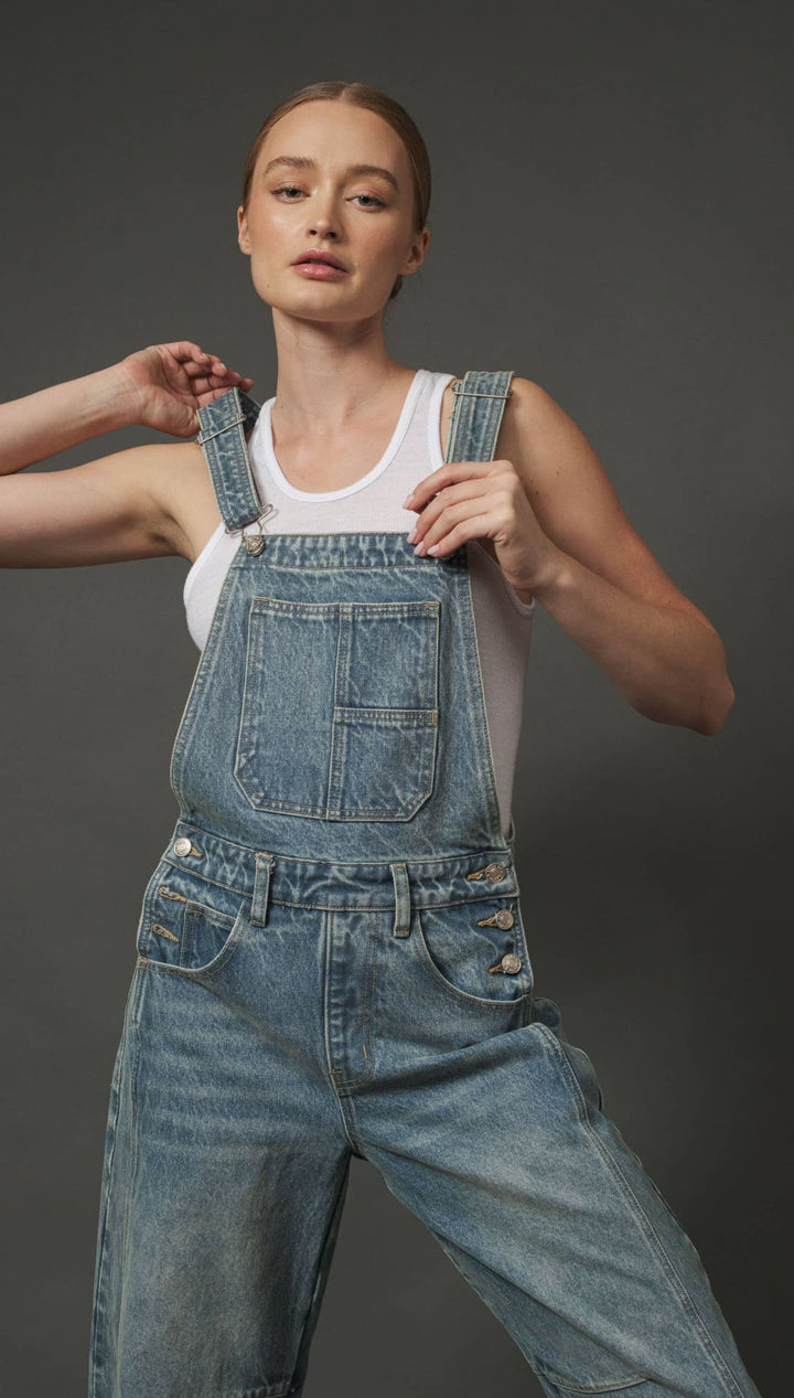 Denim overalls with a distressed look and white tank top underneath.