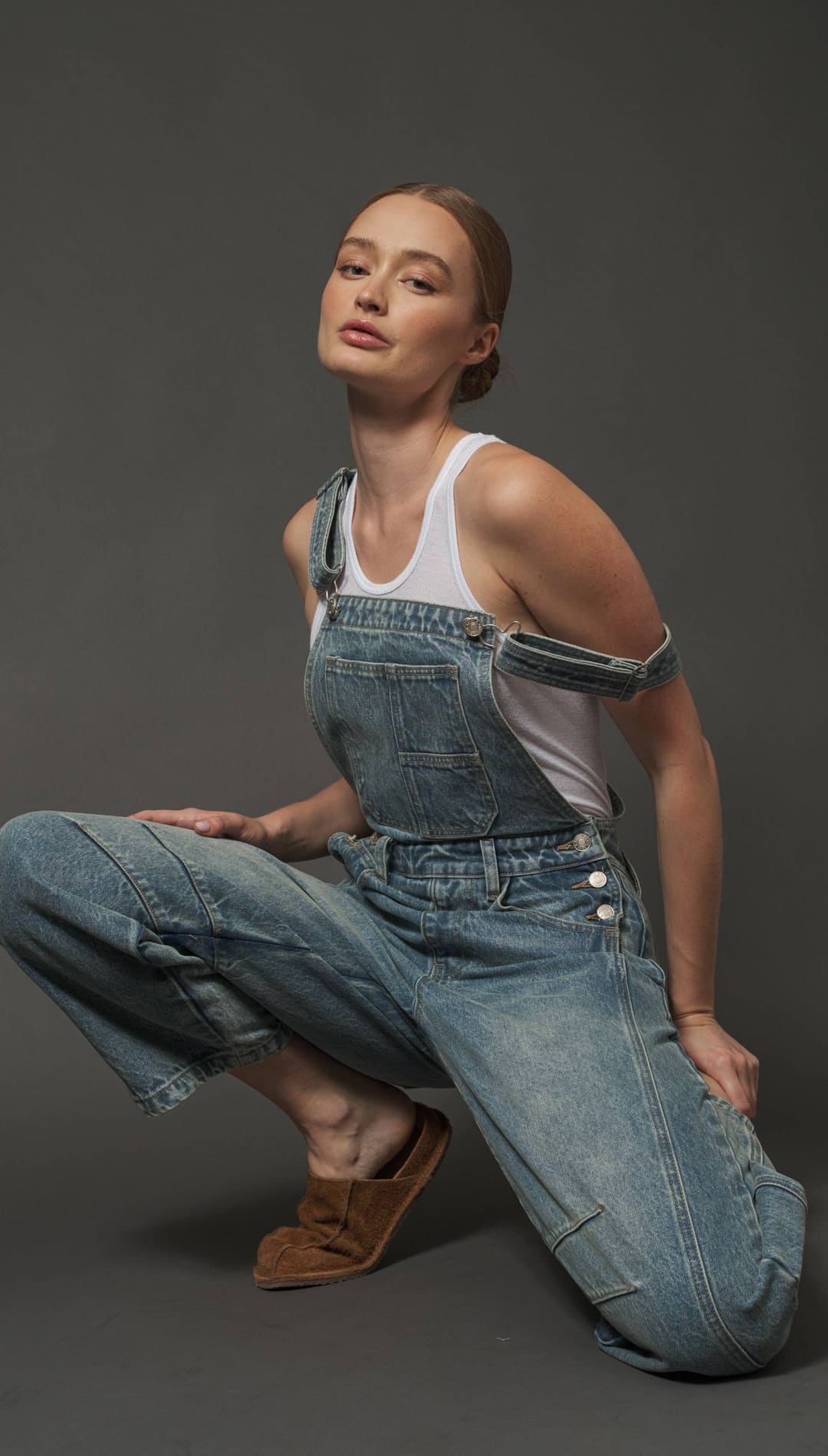 Denim overall with white tank top and brown boots.