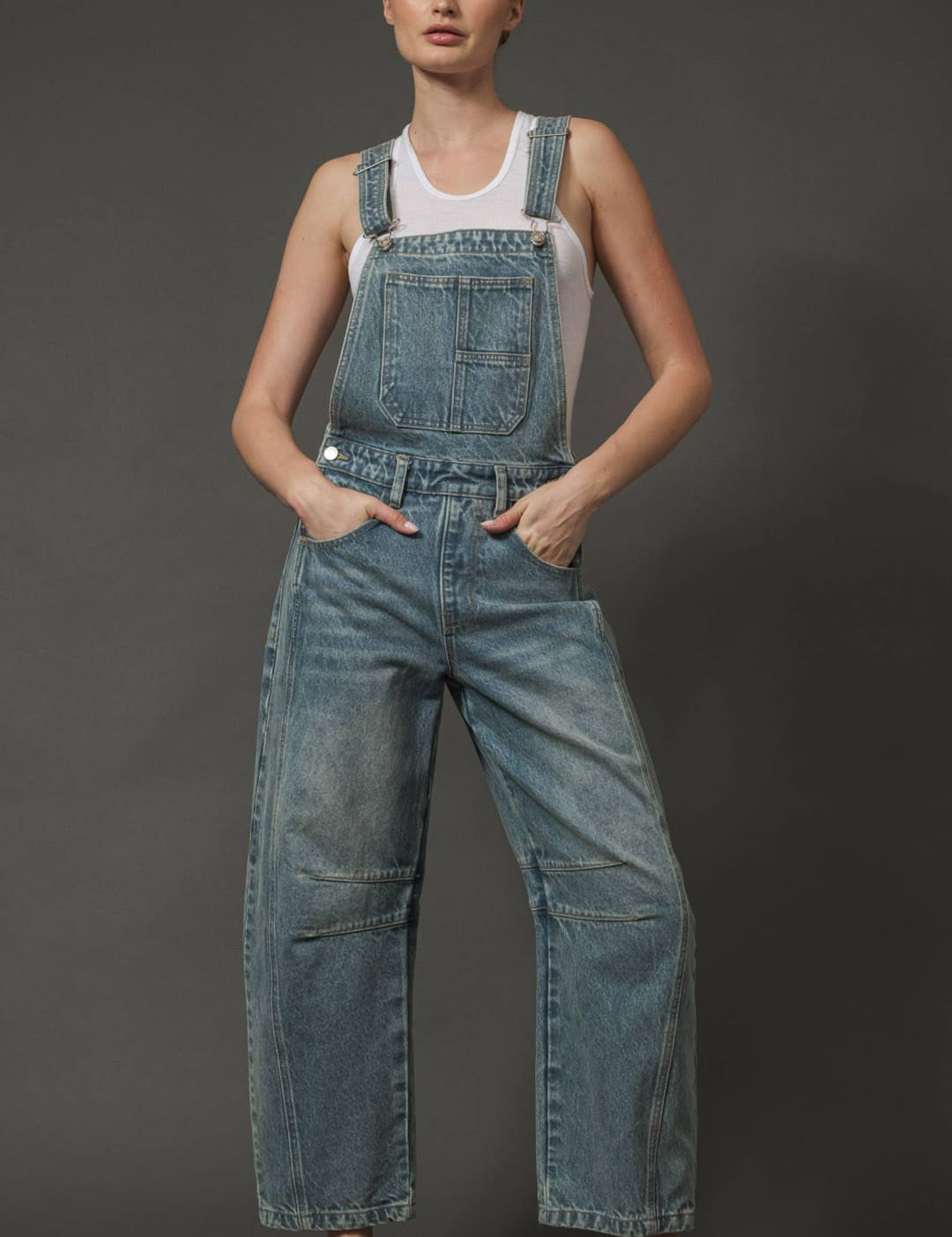 Denim overalls with a paperbag waist and side pockets, featuring brown suede mules.