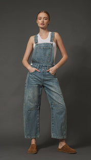 Denim overalls with a paperbag waist and side pockets, featuring brown suede mules.