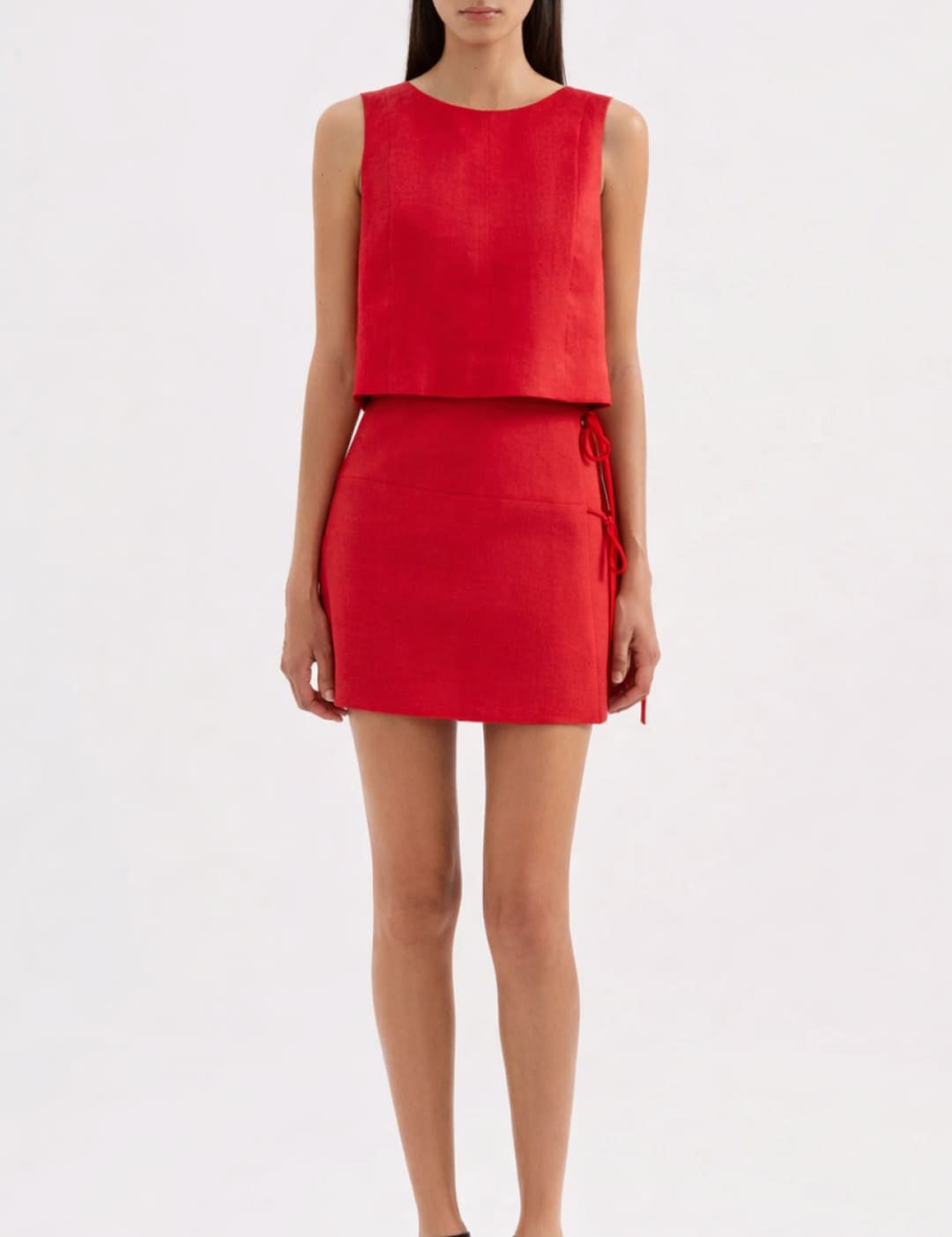 A vibrant red sleeveless mini dress with a structured bodice and skirt, featuring side ties for adjustable fit.