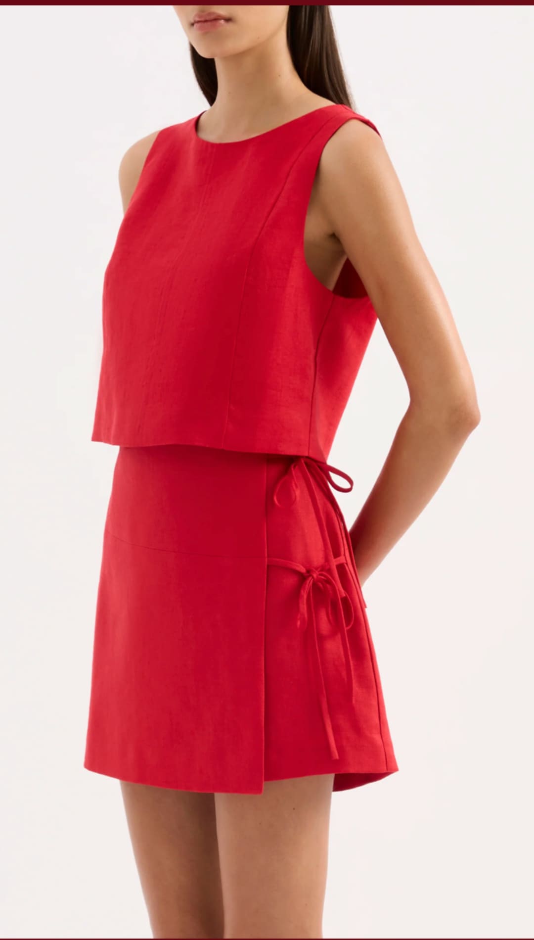 A vibrant red sleeveless two-piece outfit featuring a cropped top and flared skirt with matching fabric ties at the waist.