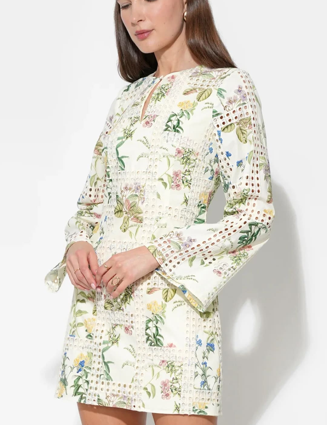 A delicate off-white mini dress adorned with a vibrant floral pattern and intricate lace detailing along the sleeves and hem.