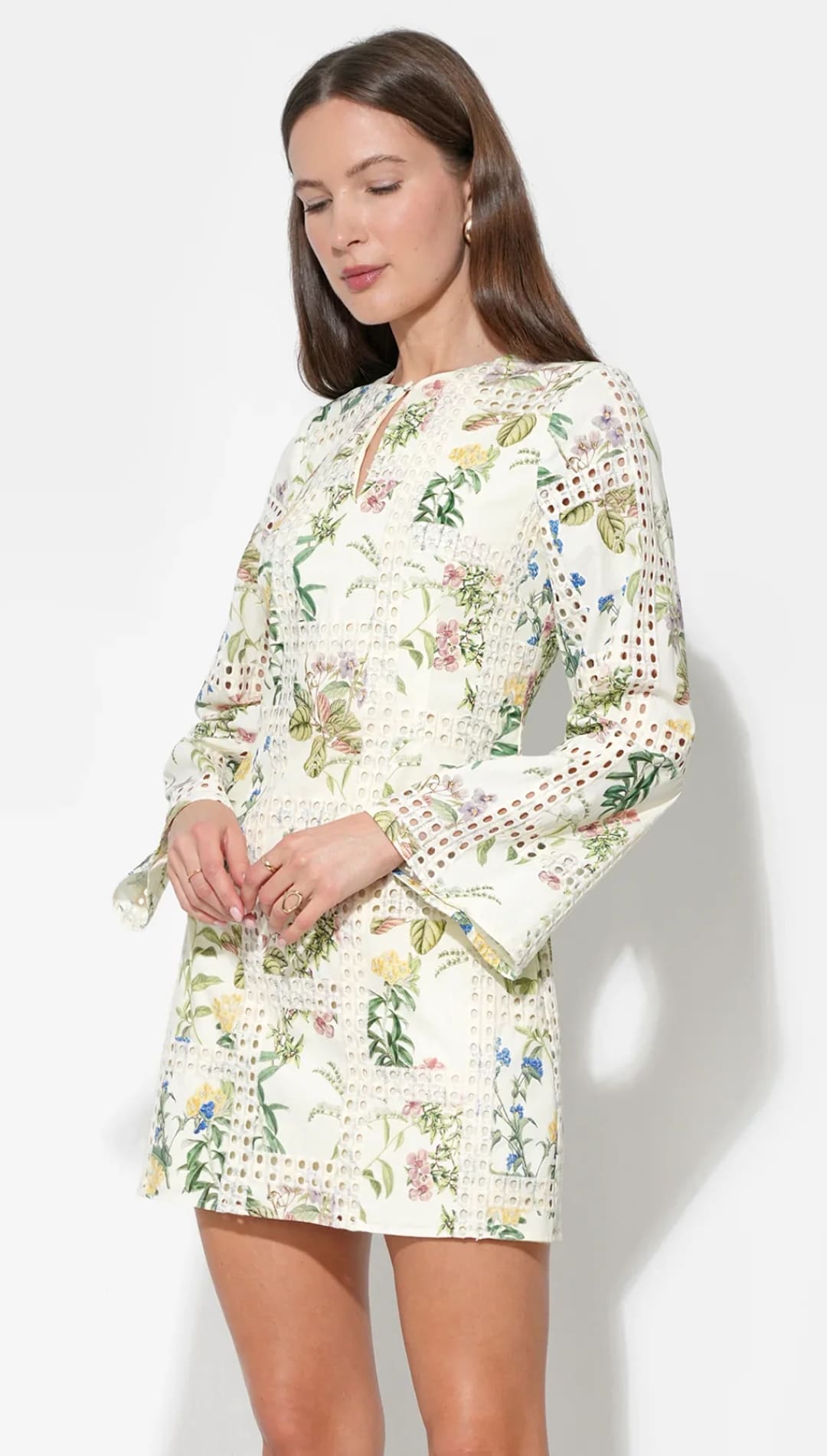 A delicate off-white mini dress adorned with a vibrant floral pattern and intricate lace detailing along the sleeves and hem.