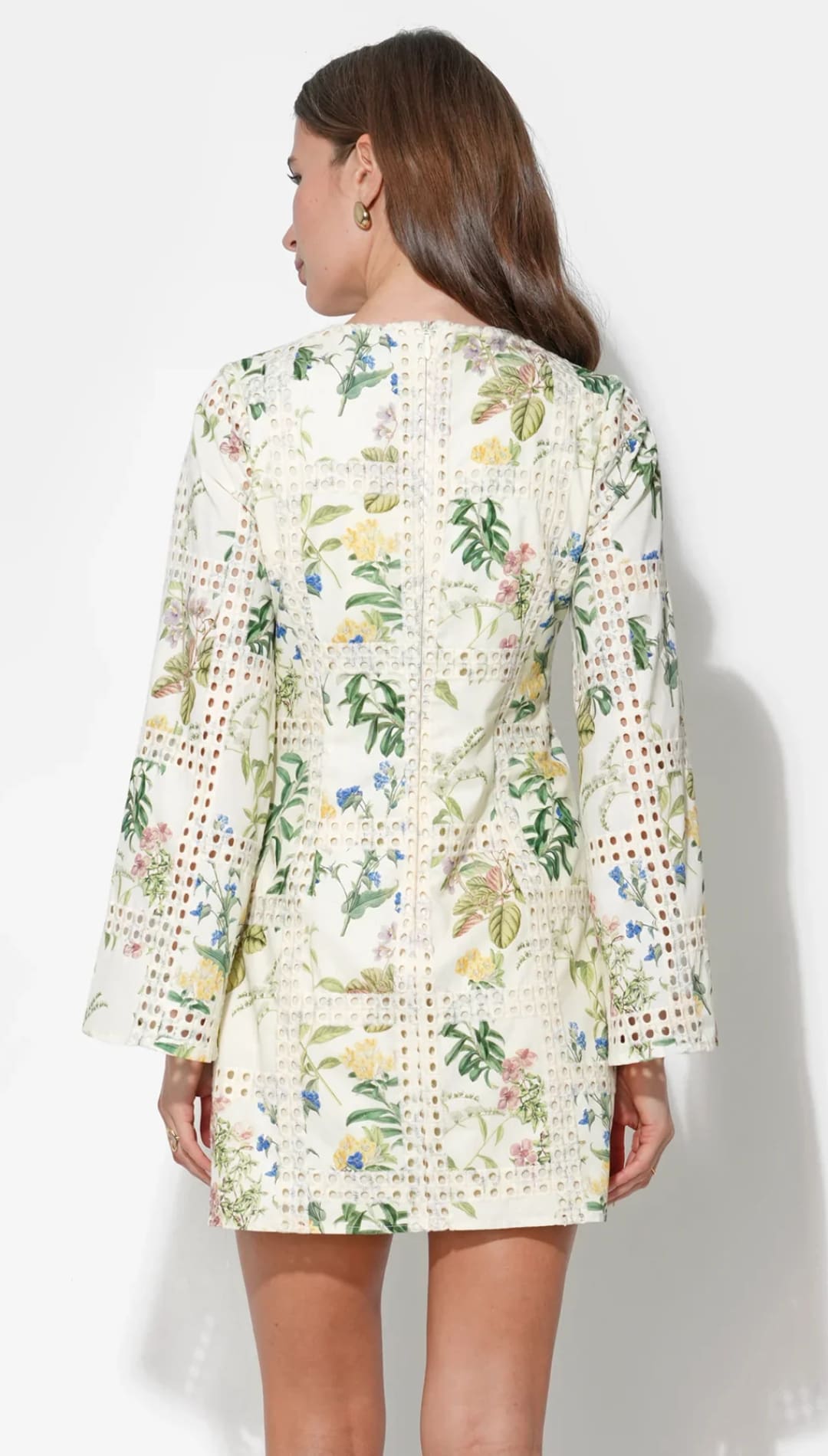 A women’s off-white mini dress featuring a vibrant floral pattern with green, yellow, and blue blossoms, accented by delicate lace detailing along the back seam.