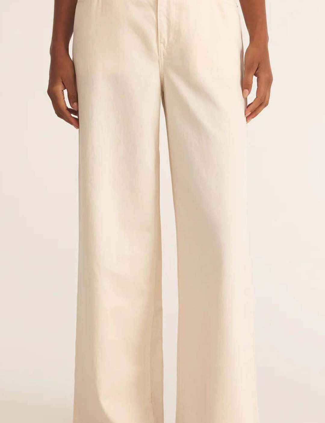 Cream-colored wide-leg pants with button details and pockets.