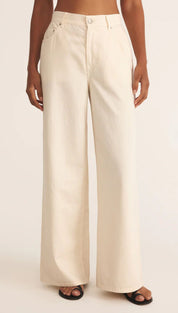 Cream-colored wide-leg pants with button details and pockets.