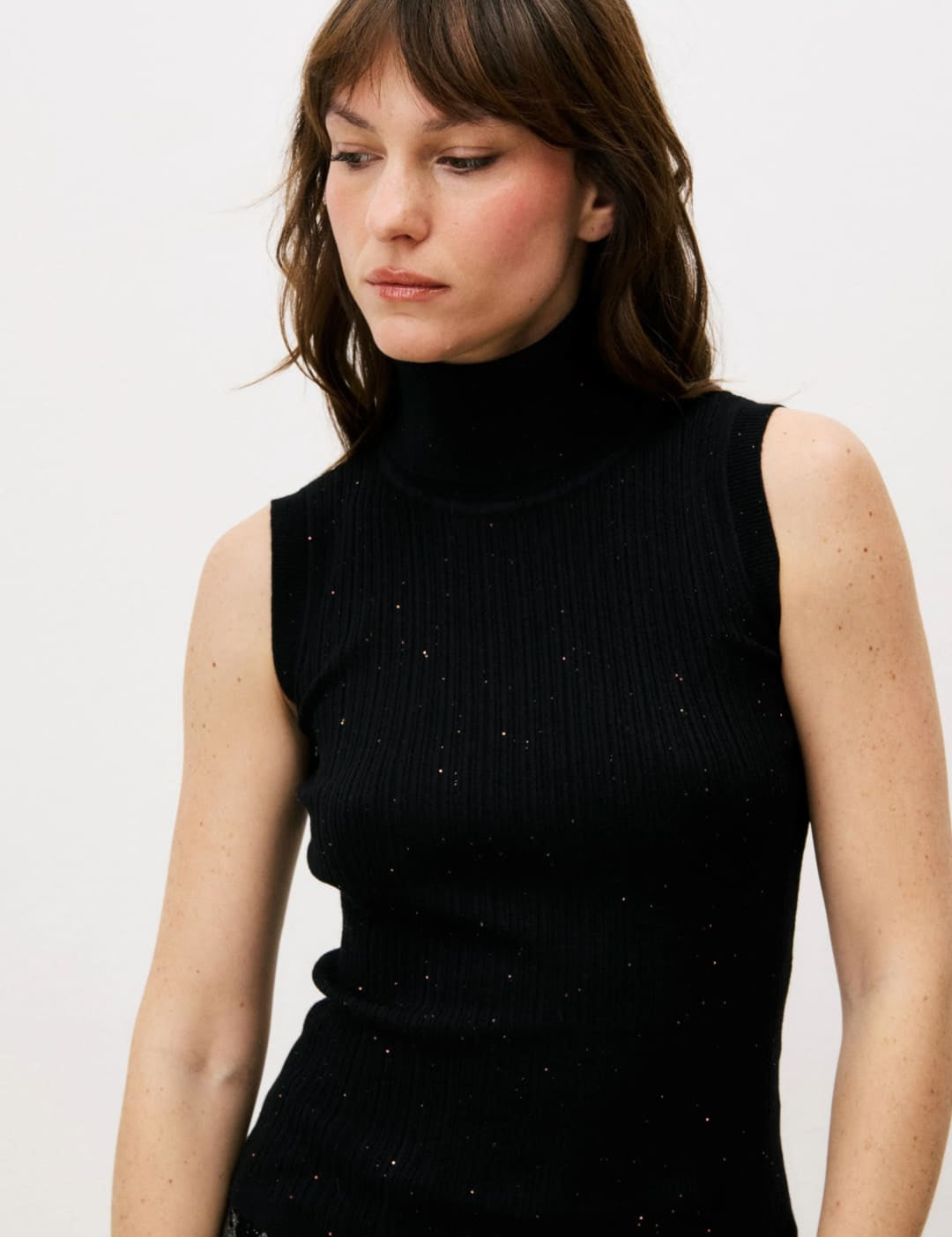 Black sleeveless turtleneck sweater with subtle glitter details.