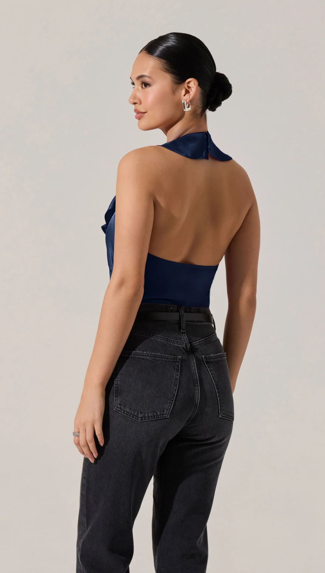 A dark blue halter-neck top with ruffled detailing and black high-waisted jeans.