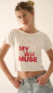 White cropped t-shirt with ’my own muse’ printed in red, surrounded by star graphics.