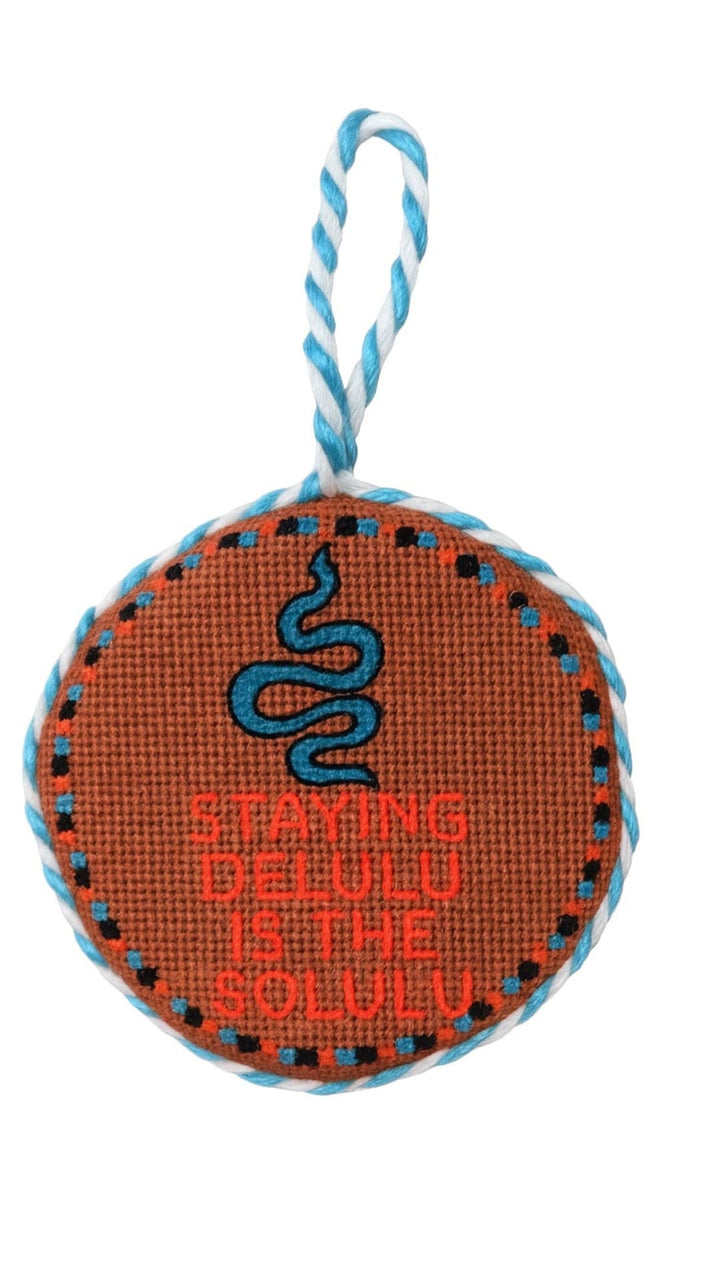 Orange cross-stitch ornament with blue snake and text ’staying cool’ on it.