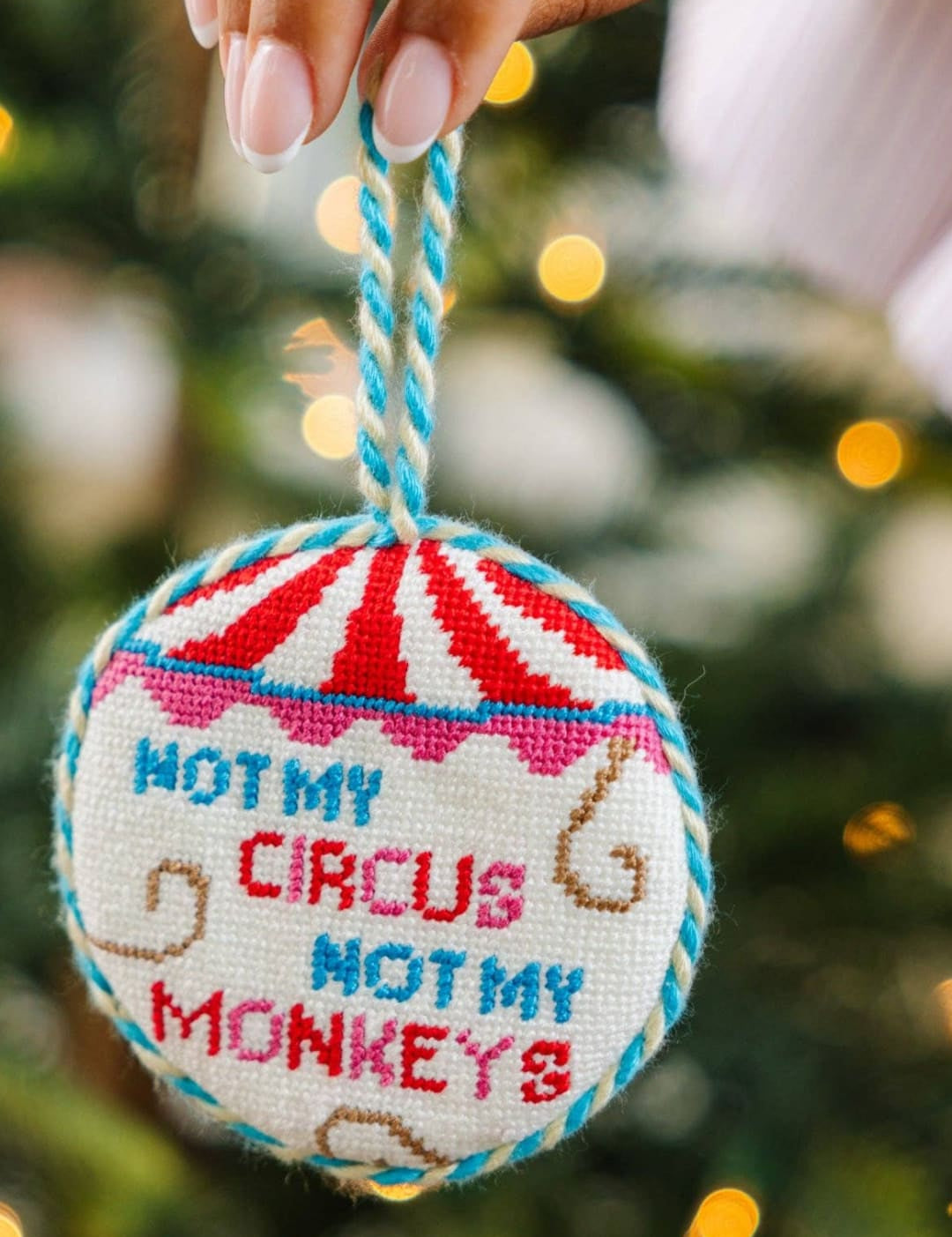 Cross-stitch ornament with ’not my circus, not my monkeys’ design on a red and white striped background.