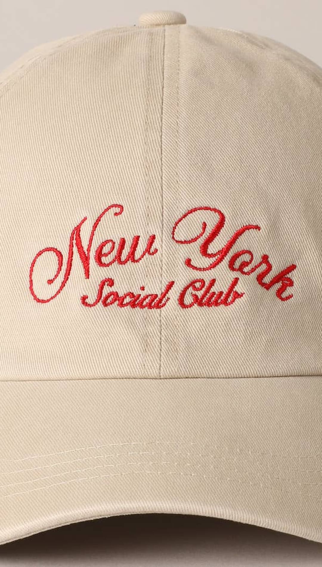 Beige baseball cap with red embroidered ’new york social club’ script.