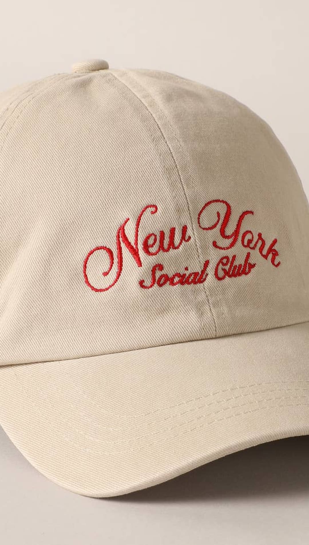 Beige cotton baseball cap with red embroidered ’new york social club’ script.
