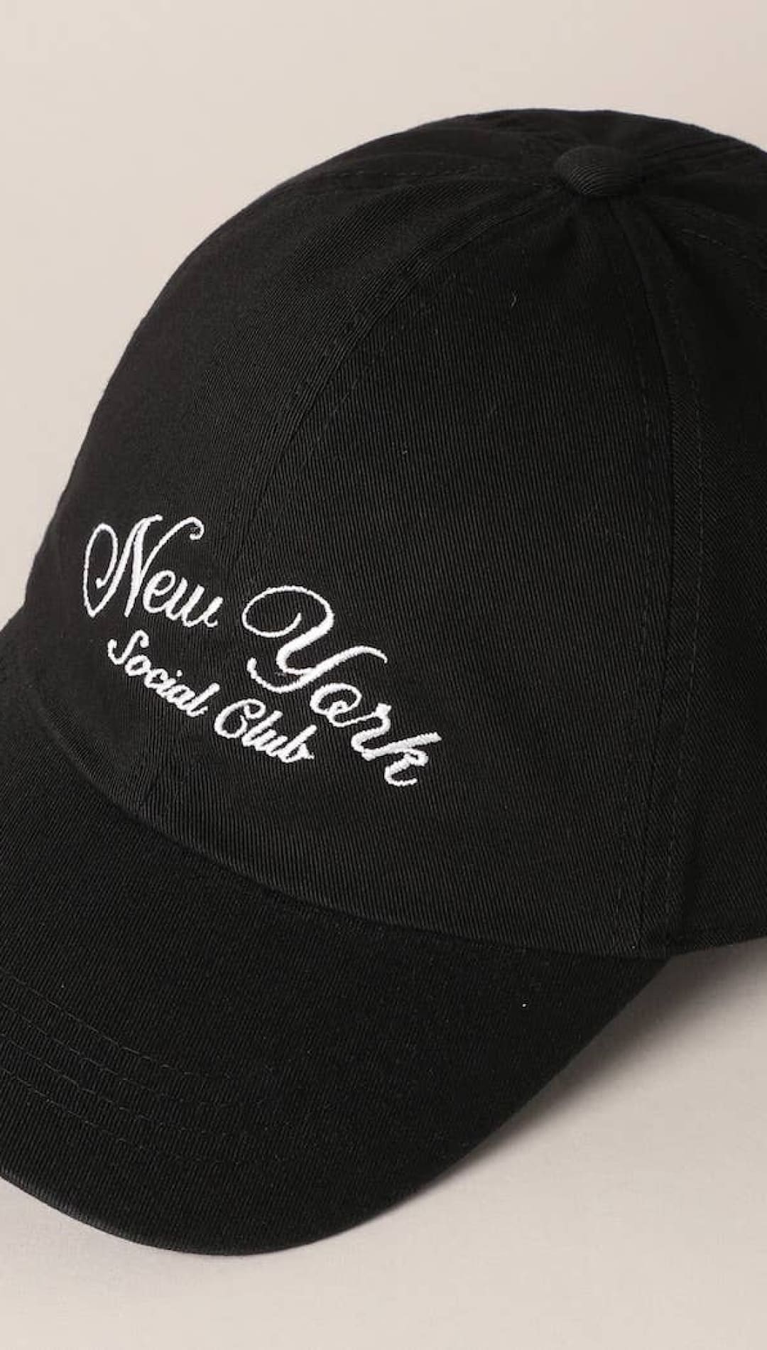 Black baseball cap with white embroidered ’new york social club’ text in a cursive script.