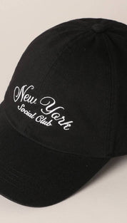 Black baseball cap with white embroidered ’new york social club’ text in a cursive script.