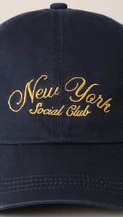 Navy blue cotton baseball cap with gold embroidered ’new york social club’ script across the front