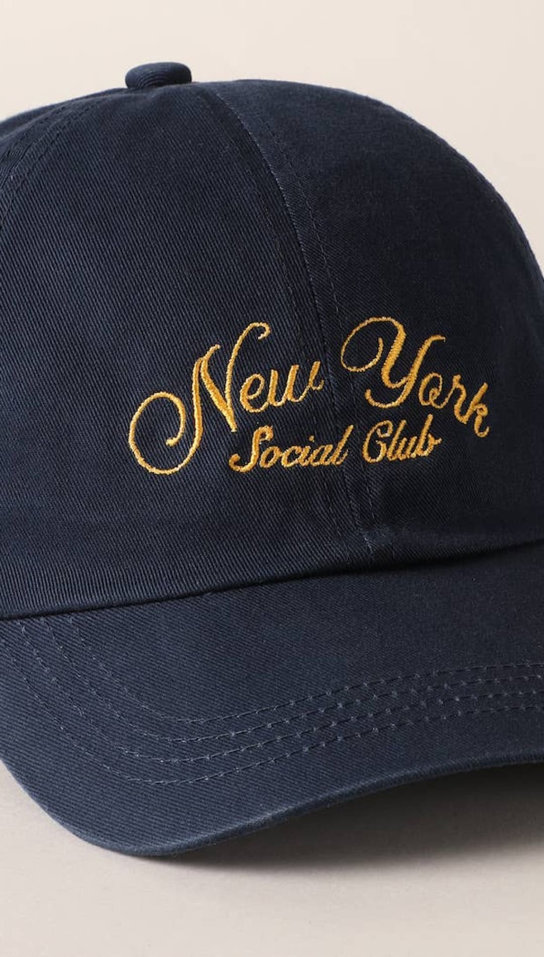 Navy blue cotton baseball cap with gold embroidered ’new york social club’ script across the front
