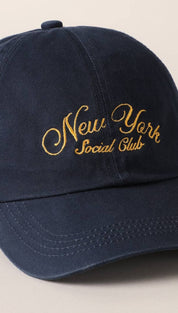 Navy blue cotton baseball cap with gold embroidered ’new york social club’ script across the front