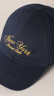 Navy blue cotton baseball cap with gold embroidered ’new york social club’ script across the front