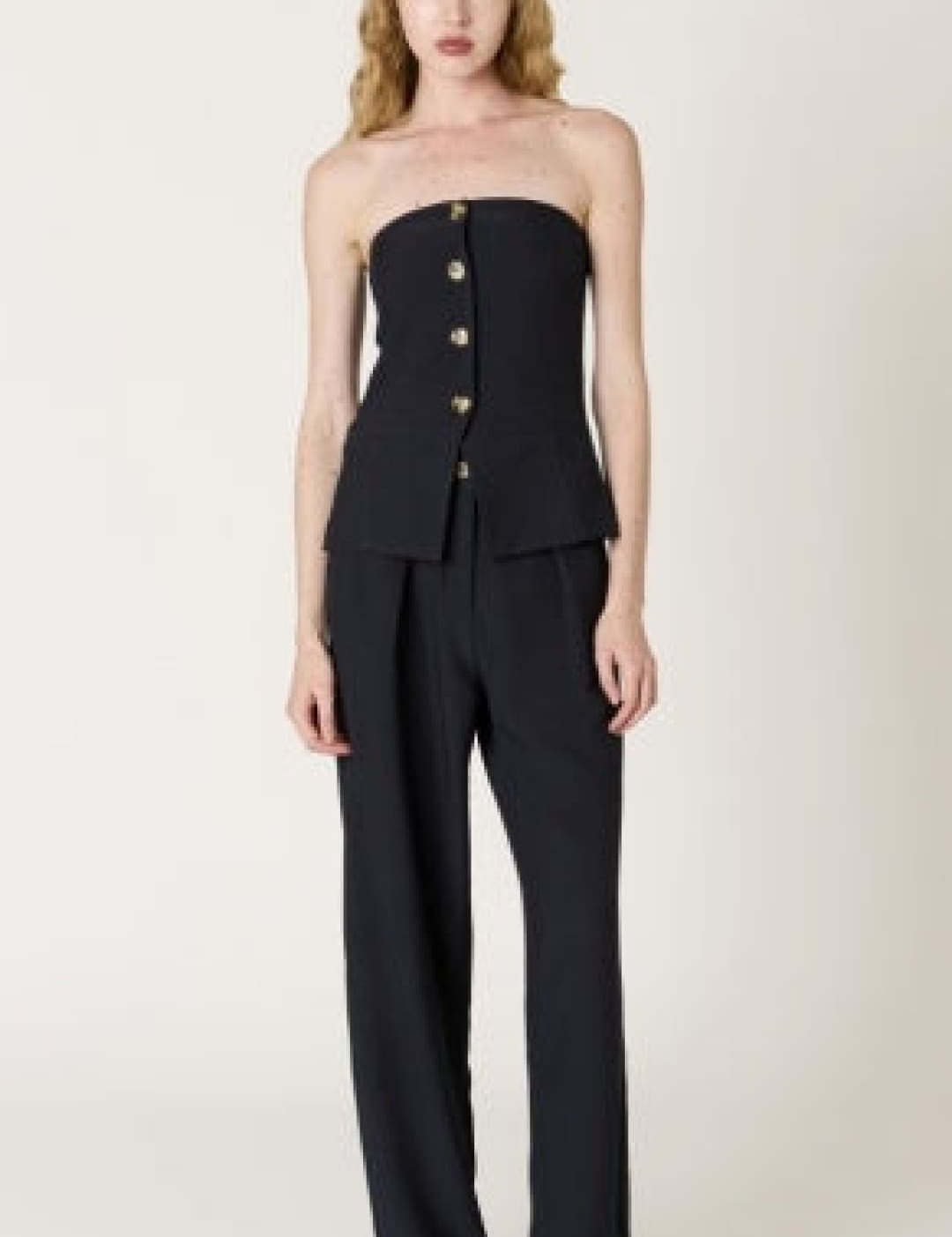 Black strapless corset top with button detailing and matching wide-leg trousers.