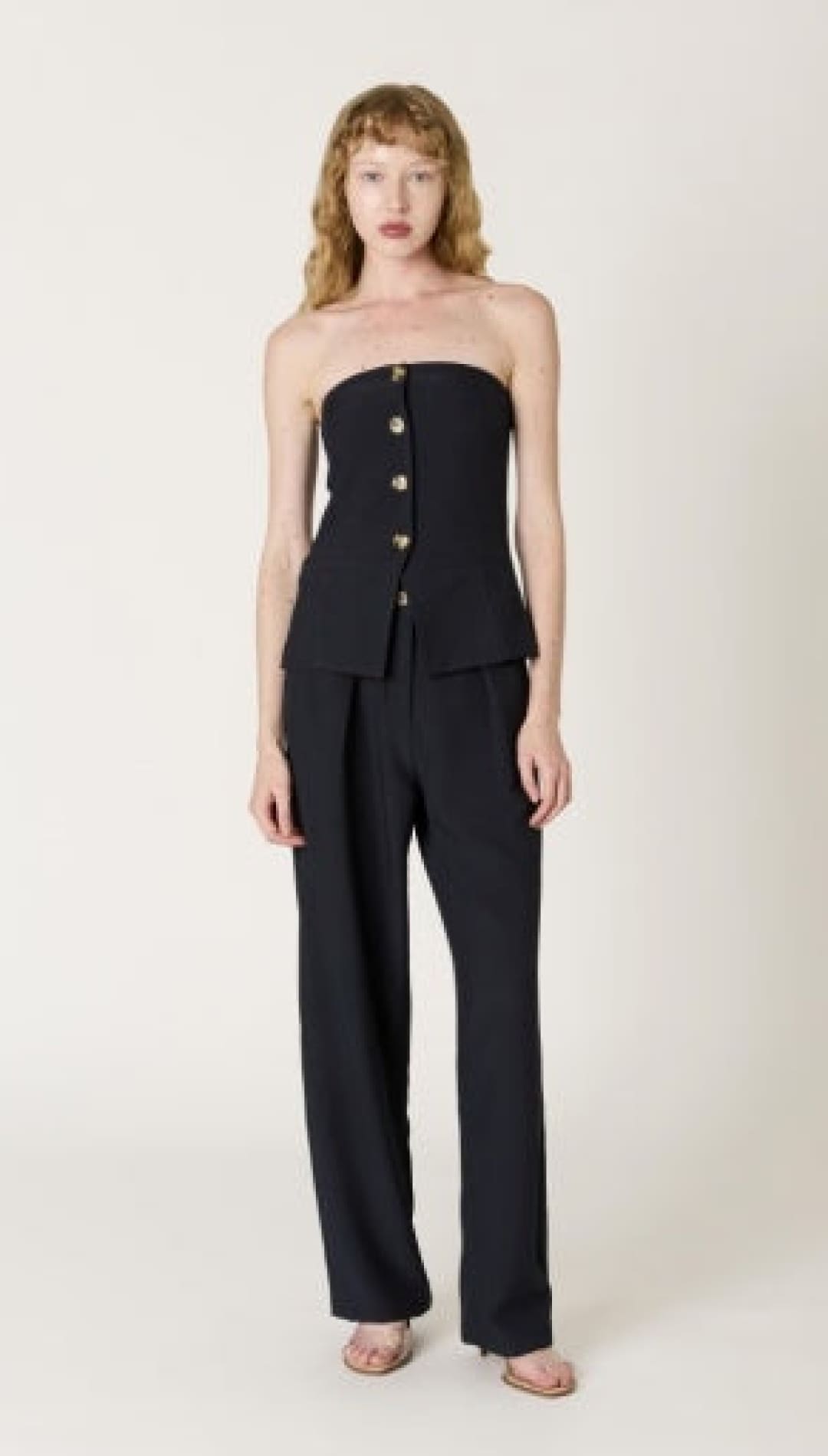 Black strapless corset top with button detailing and matching wide-leg trousers.
