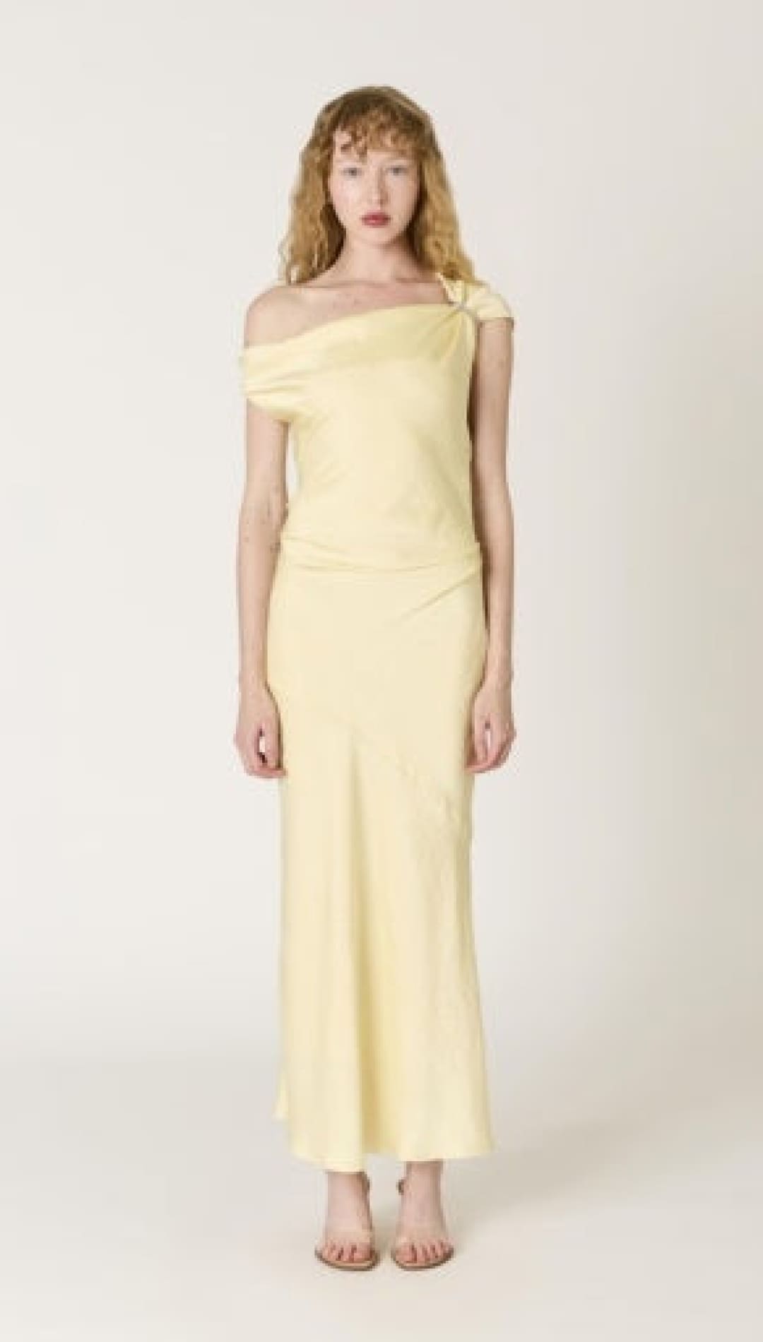 A pale yellow satin off-the-shoulder maxi dress with a sleek, flowing silhouette.