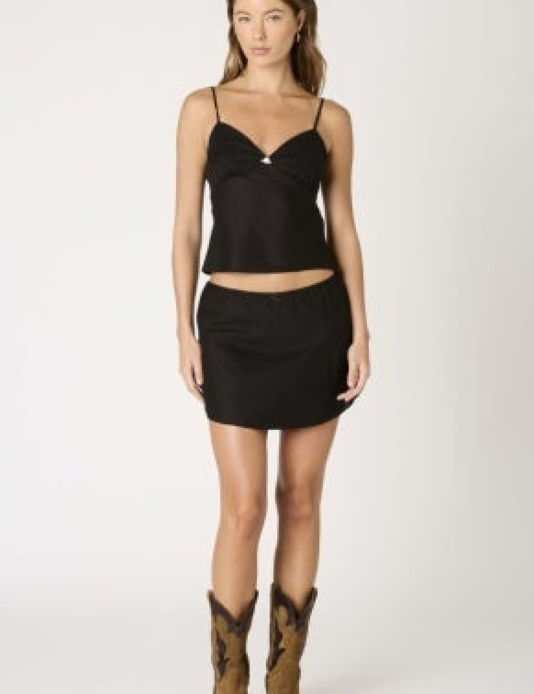 Woman in black top and skirt with cowboy boots.