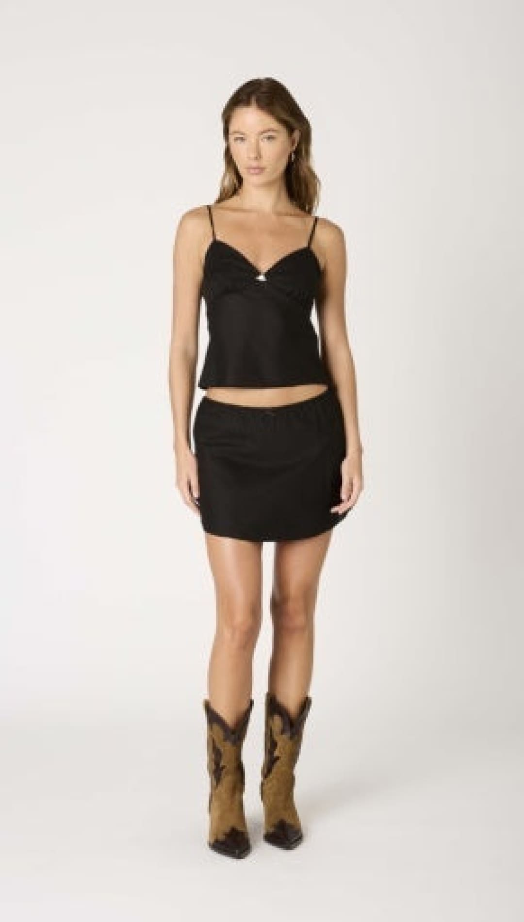 Woman in black top and skirt with cowboy boots.