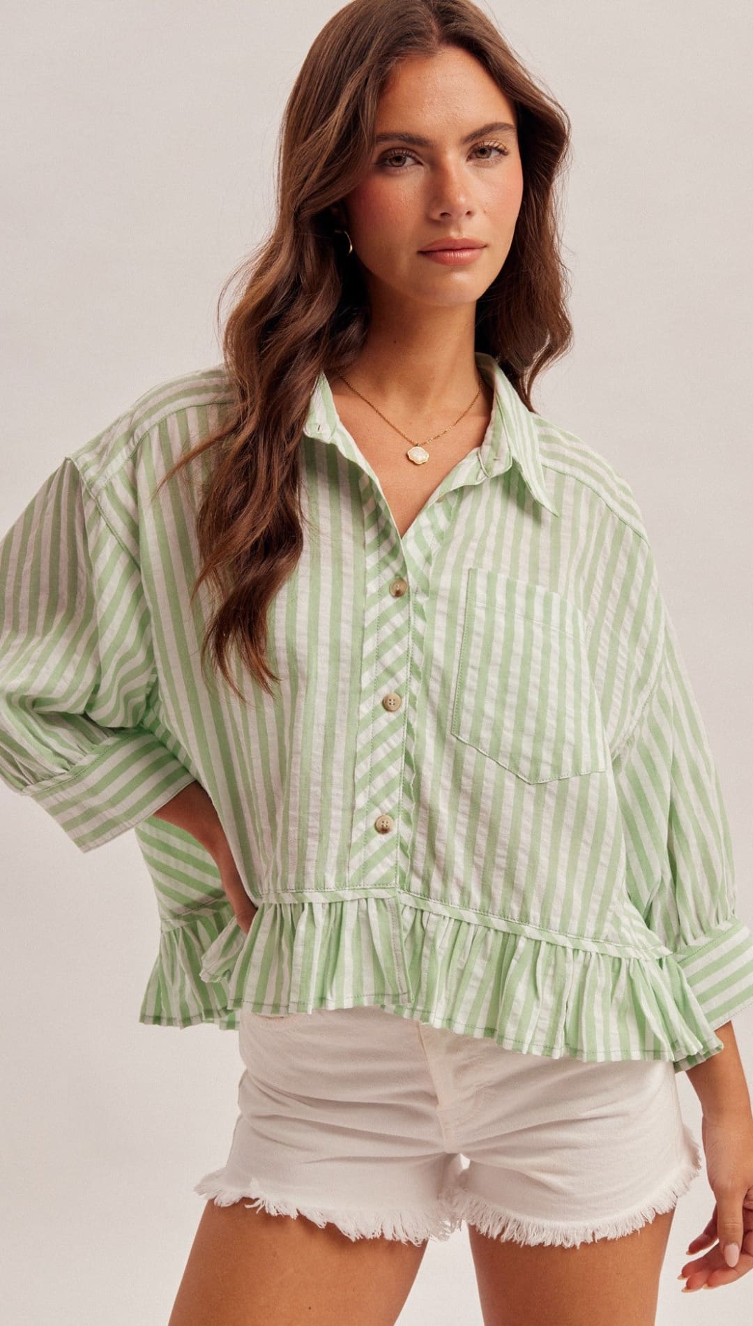 Light green and white vertically striped button-up blouse with ruffled hem and puff sleeves.