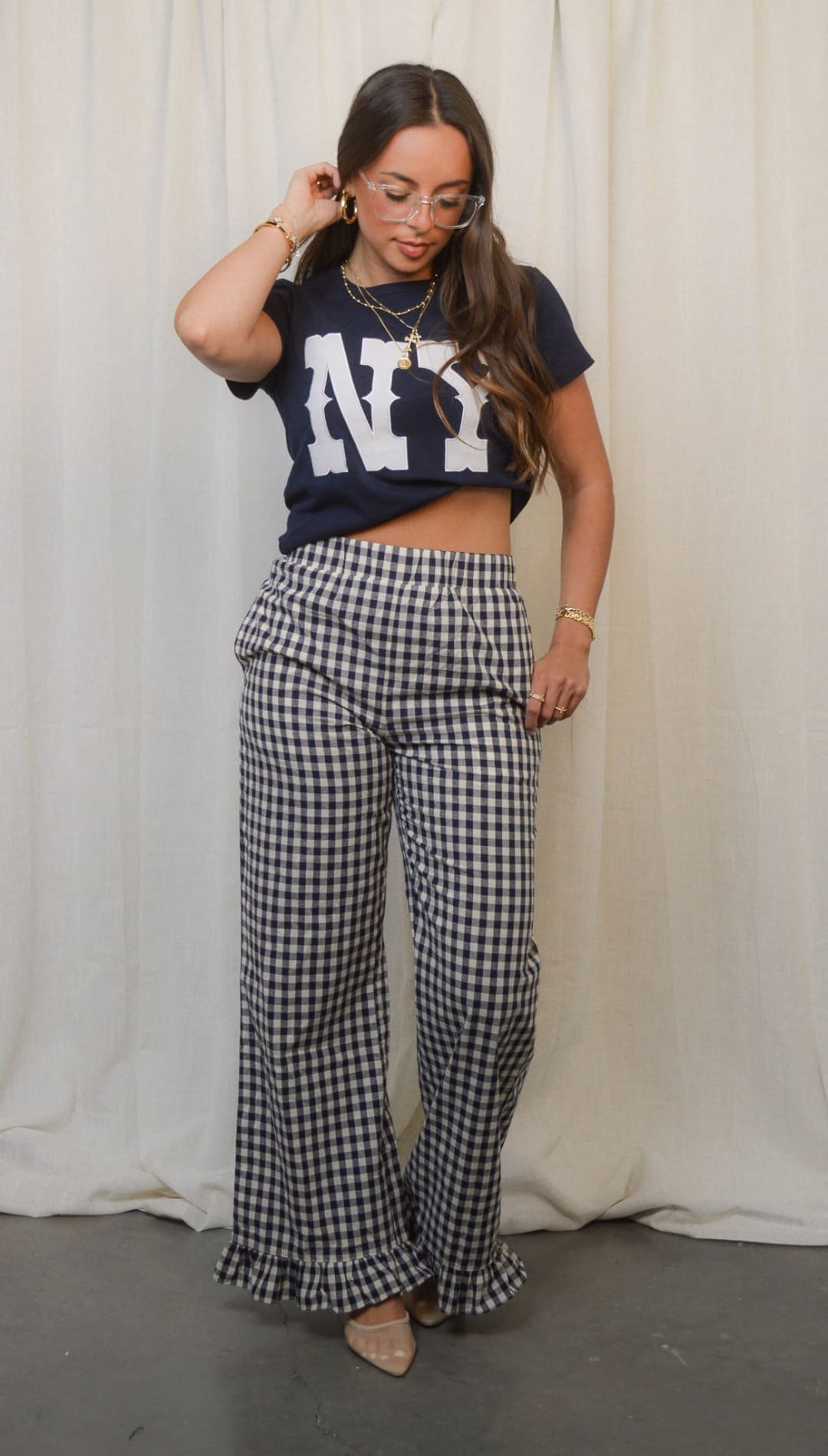 Navy blue cropped t-shirt with ’NY’ in white block letters, paired with black and white gingham wide-leg pants featuring ruffled hems.