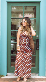 Woman in a polka dot dress standing in front of a teal door.