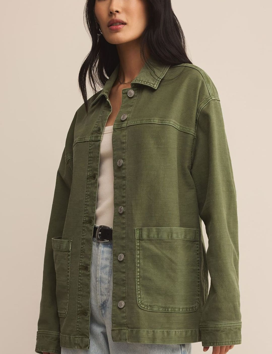 Woman wearing an olive green utility jacket and light wash jeans.