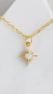 Gold chain necklace with starburst pendant.
