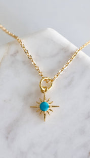 Gold chain necklace with turquoise starburst pendant.