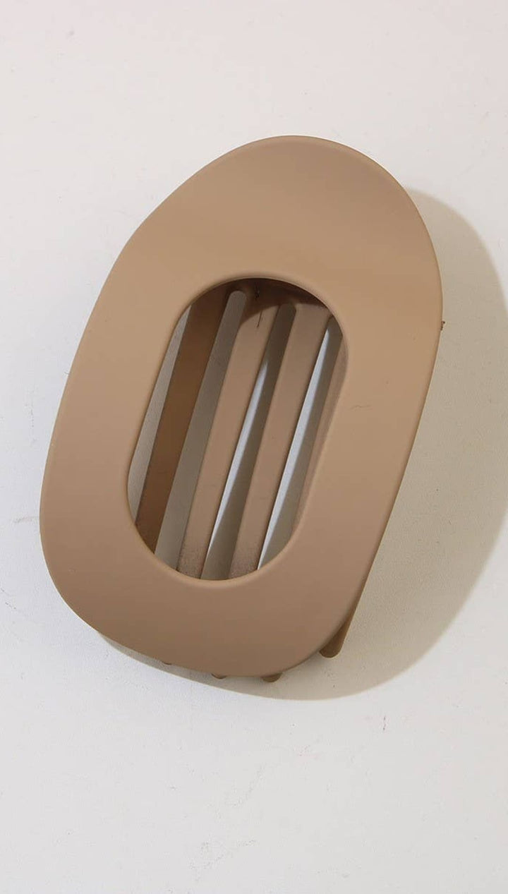 Beige oval-shaped belt buckle with horizontal slits for fastening.
