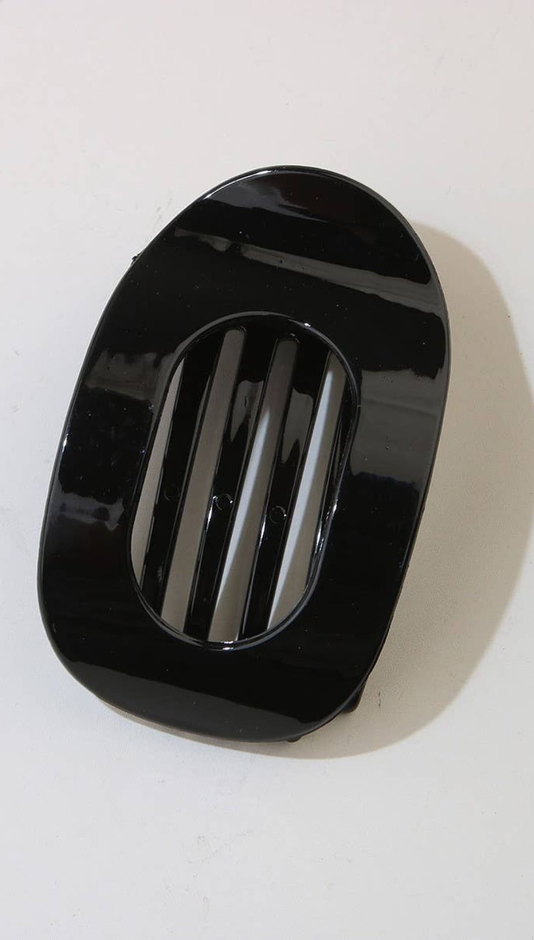Black glossy car vent cover with three horizontal slits for air flow.