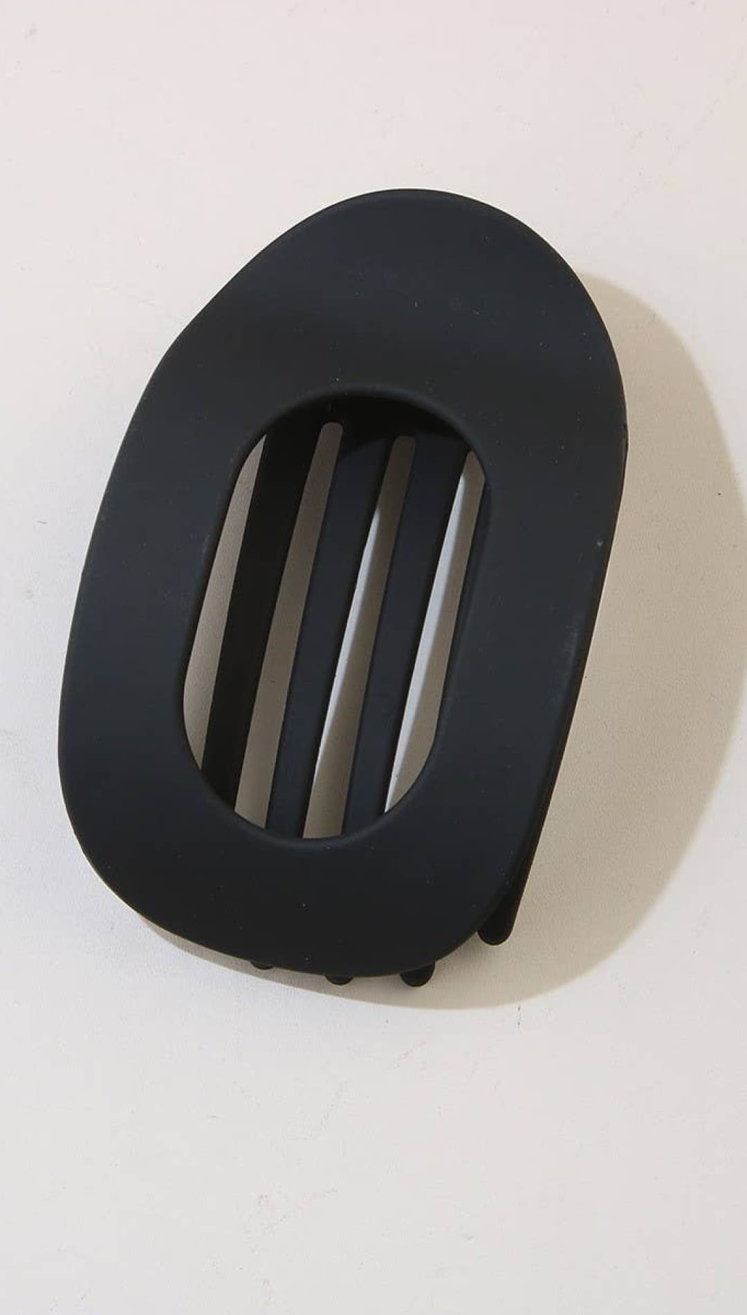 Black oval-shaped belt buckle with horizontal slits and textured edges.