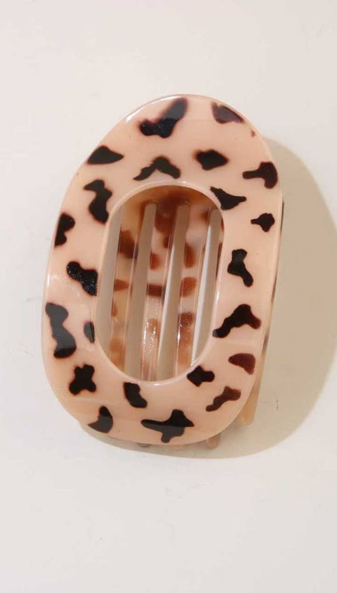 Leopard print hair clip with pink and black spots on a white background.