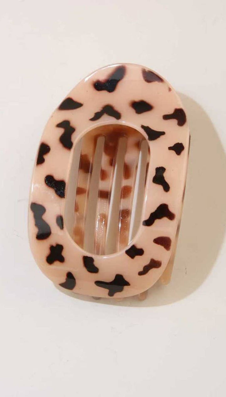 Leopard print hair clip with pink and black spots on a white background.