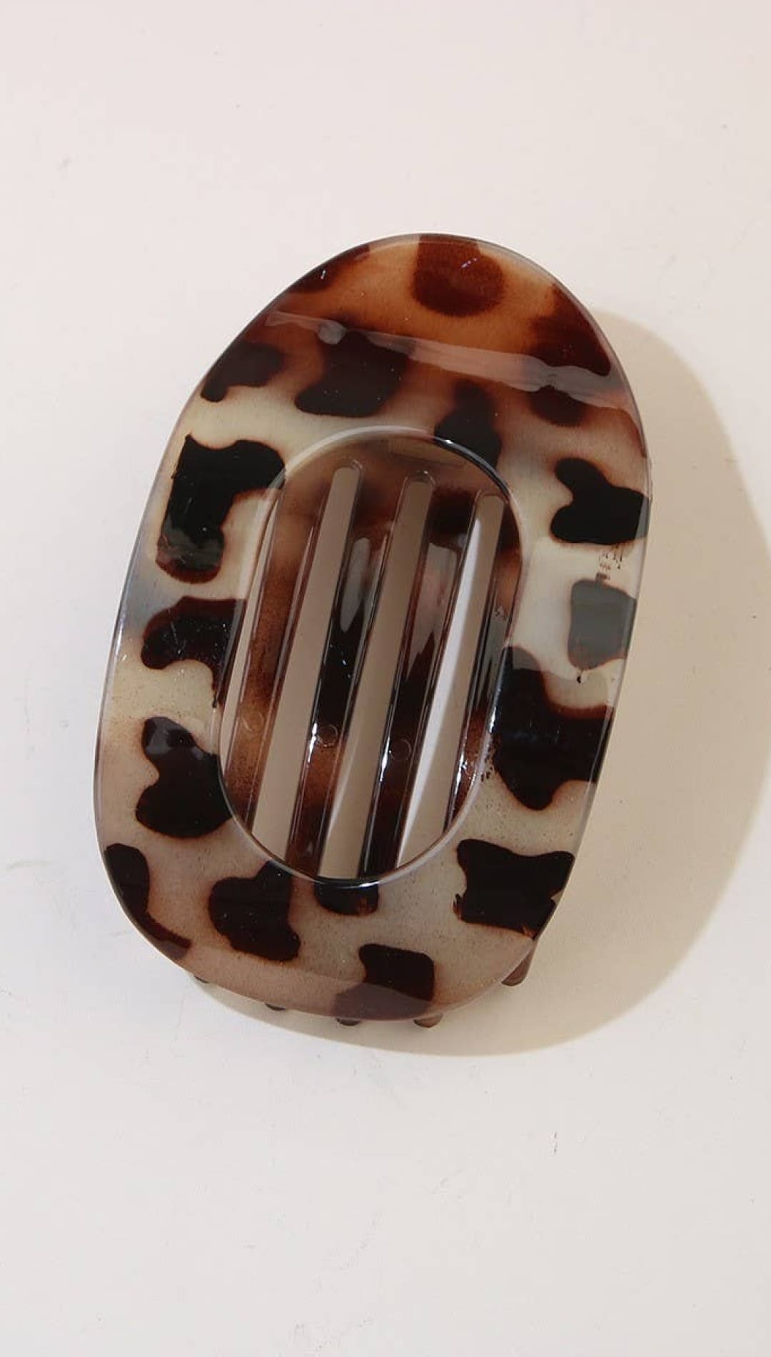 Tortoiseshell oval hair clip with a sleek black center bar.