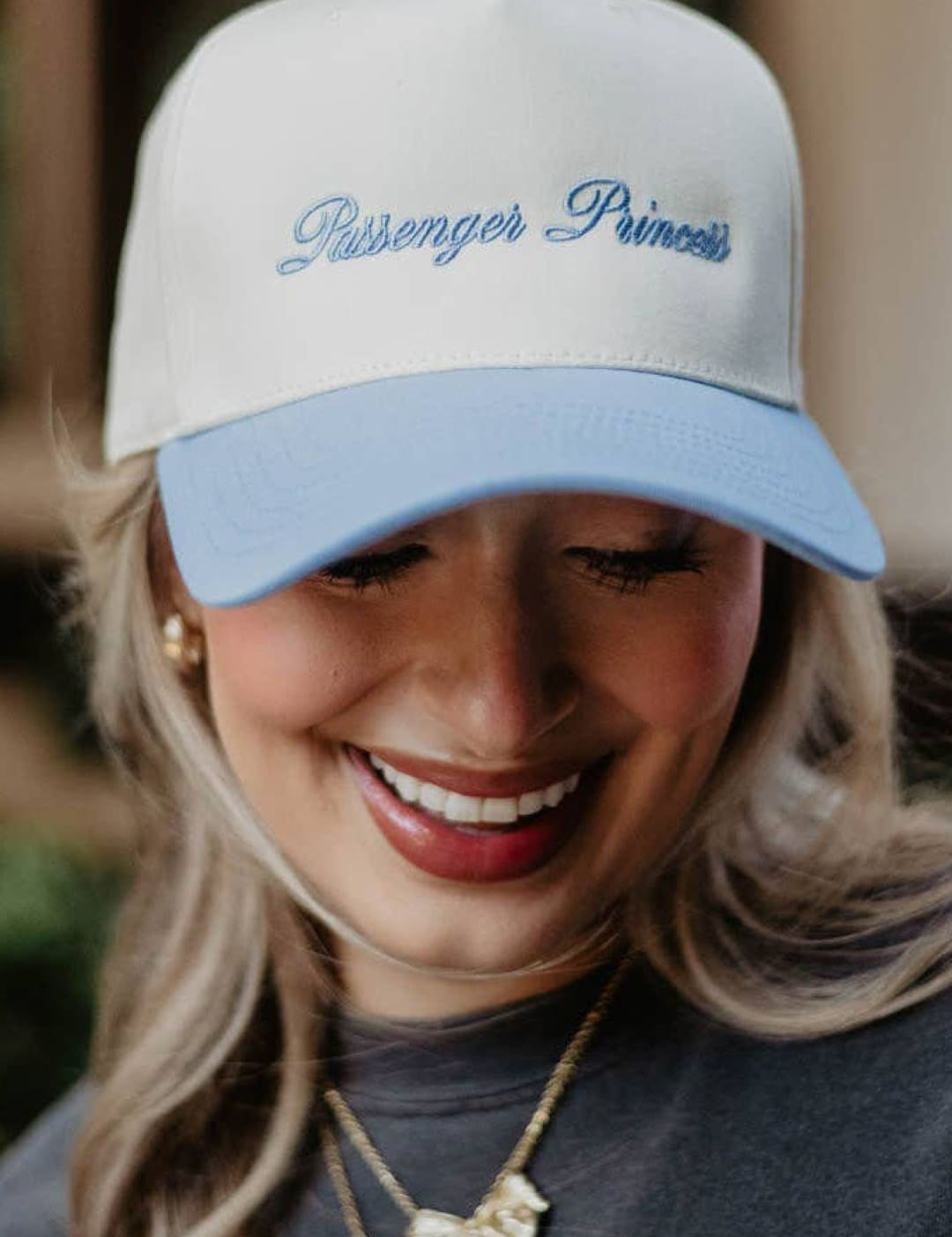 White and light blue ’passenger princess’ baseball cap with embroidered text, cotton material.